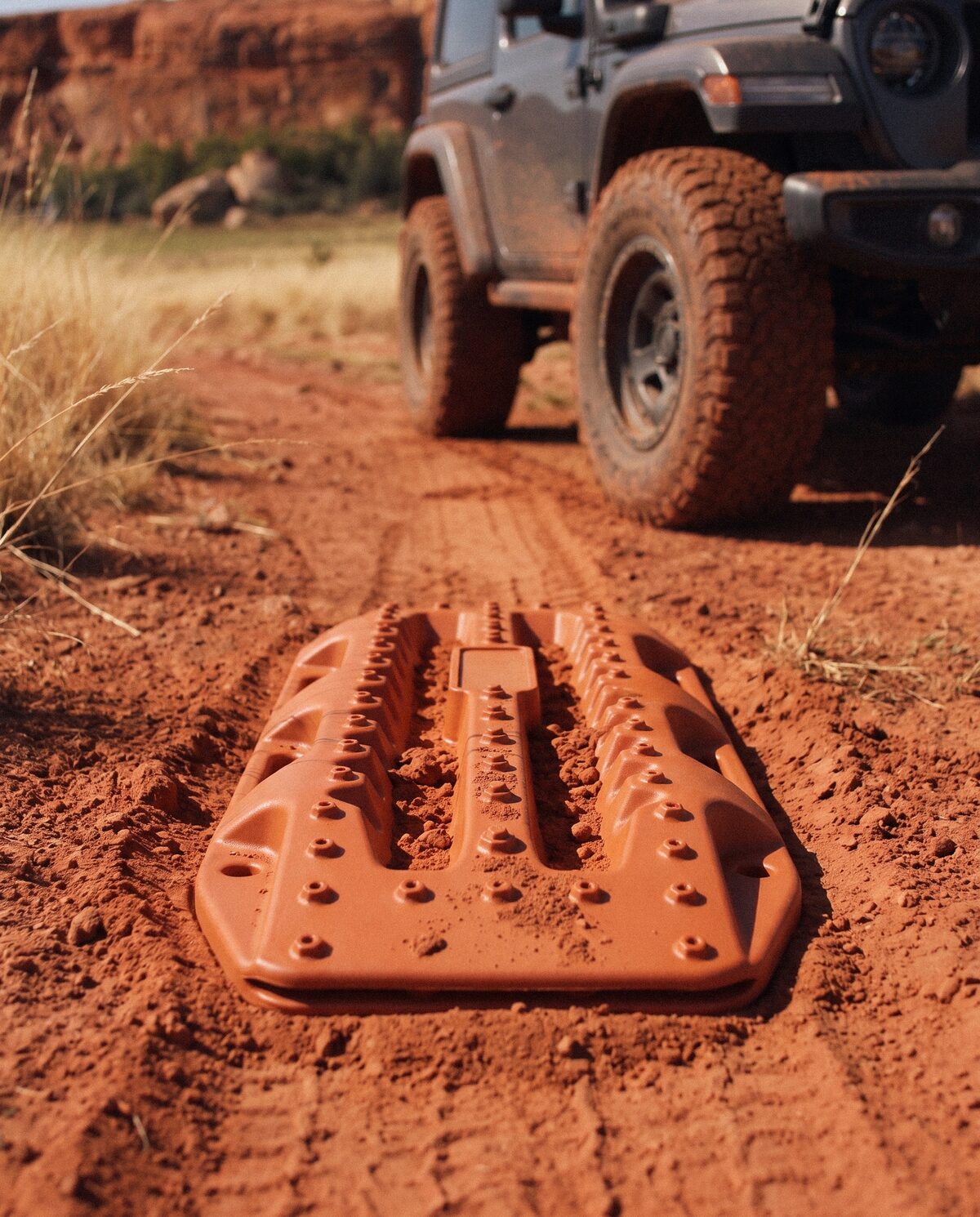 Recovery board pressed into red dirt with a fresh tyre print, 4WD behind
