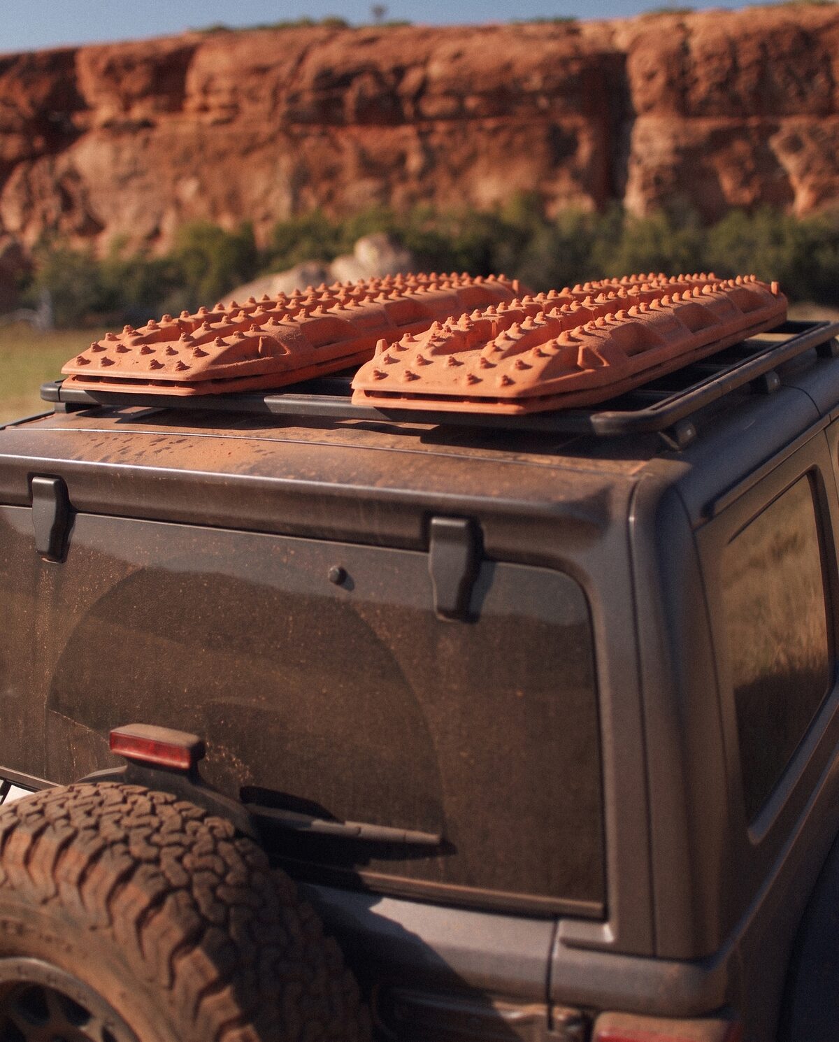 Close detail of recovery boards strapped to a roof rack, red cliffs behind